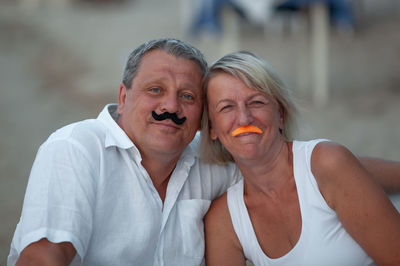 Portrait of mature couple with mustache props at beach