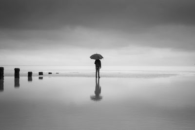 Rear view of man looking at sea against sky