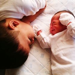 High angle view of siblings lying down on bed at home