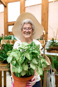 Portrait of woman wearing hat standing against plants