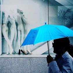 Side view of man holding umbrella by shop