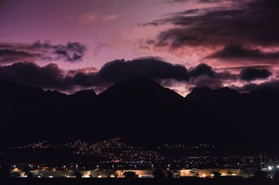 Silhouette of illuminated mountain against dramatic sky