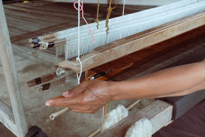 Cropped hand waving textile on loom in factory