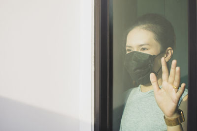 Portrait of man covering face with window
