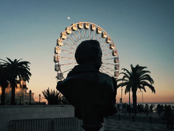 Bust against ferris wheel during sunset