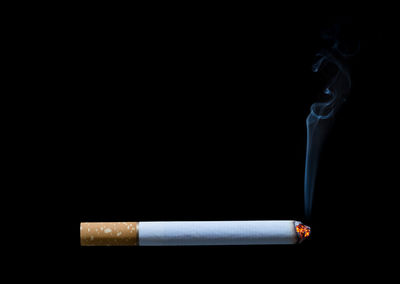 Close-up of cigarette smoking against black background