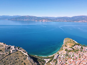 Aerial view of sea and mountains against blue sky