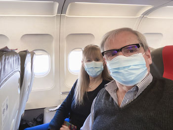 Portrait of senior couple wearing mask sitting at airplane