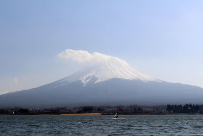 Scenic view of sea by snowcapped mountain against sky