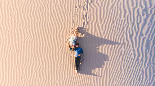High angle view of couple lying on sand at desert