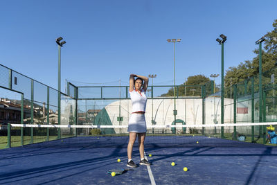 Young woman exercising at sports court on sunny day