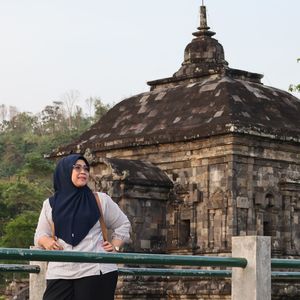 Portrait of young woman standing against building