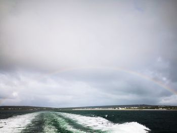 Scenic view of rainbow over sea against sky