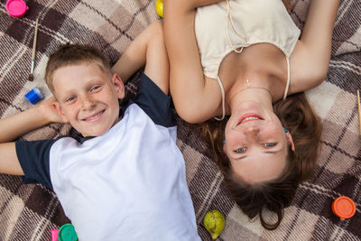 High angle view portrait of siblings lying on bed