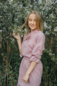 Blonde girl on a spring walk in the garden with cherry blossoms. female portrait, close-up. 