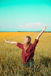 Woman with arms raised on field against sky