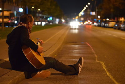 Man sitting on road at night