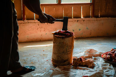 Low section of man cutting meat on cutting board