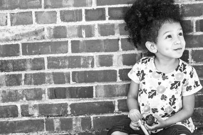 Close-up of girl against brick wall