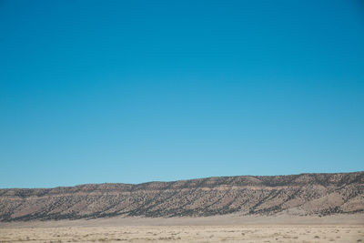 Scenic view of desert against clear blue sky