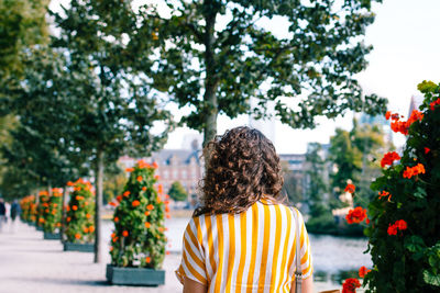 Rear view of woman standing by flowering plants