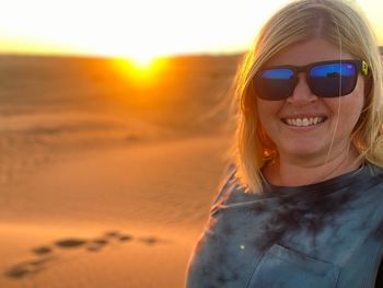 Portrait of smiling woman wearing sunglasses against sky during sunset