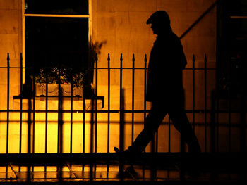 Silhouette man standing by railing against building at night