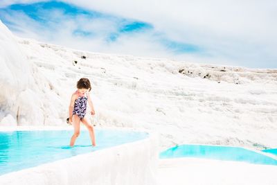 Full length of young woman standing on snow covered mountain