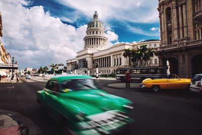 Blurred motion of cars on road outside cathedral against sky in city