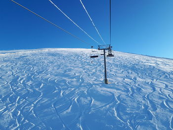 Snow covered landscape against clear blue sky