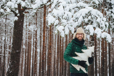 Portrait of smiling man in snow covered tree