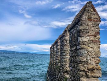 Stone wall by sea against sky