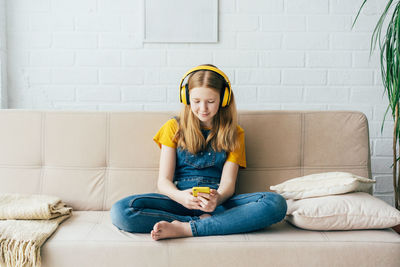 Full length of woman sitting on sofa at home