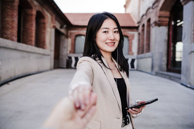 Confident beautiful chinese business woman using mobile phone in city.holding hand with friend. pov