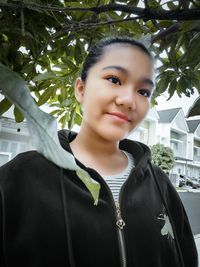 Portrait of smiling girl standing against tree