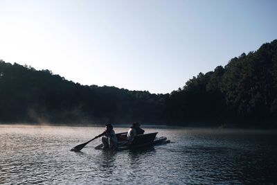 People in boat on river against sky