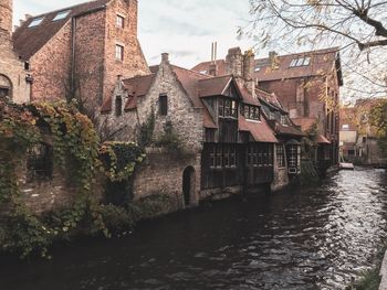 Buildings by river against sky