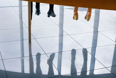 Low section of woman reflecting on tiled floor