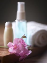 Close-up of pink flowers with beauty products on table