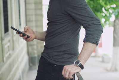 Midsection of man using mobile phone in balcony