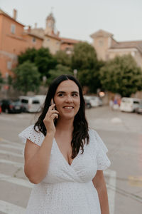 Candid portrait of happy young woman talking on the phone in city