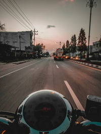 Cars on road in city against sky during sunset