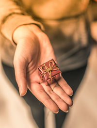 Close-up of woman hand holding small wrapped gift at home