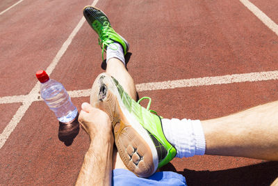 Low section of athlete with torn shoes sitting on track