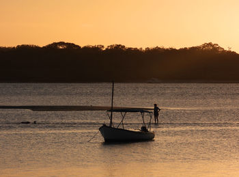 Silhouette boat in lake against sky during sunset