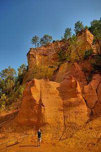 Woman standing on rock formation against sky