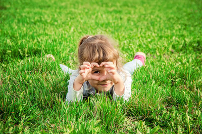 Rear view of girl playing with flowers on field