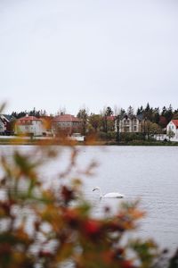 Buildings by river against clear sky