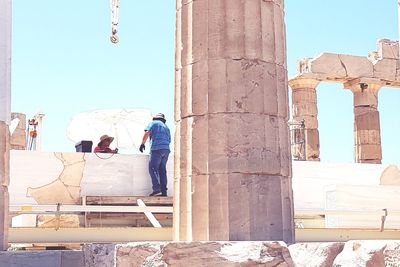 People in historic building against clear sky