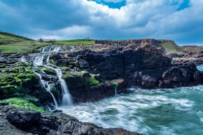 Scenic view of waterfall against sky